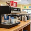 Coffee vending machines for school canteen on wooden counter with cups and supplies