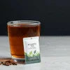 Sugar-free tea premix for offices served in a clear glass with product packet beside it