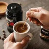 Instant masala chai premix with hand stirring tea in a cup surrounded by spices and jars