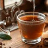 Indian masala tea premix for office poured into a glass cup on a wooden table
