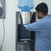 Buy water dispenser for office Noida showing man using water cooler in workspace