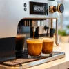 Nescafe coffee machine brewing two cups of espresso with rich crema