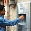Man using a commercial coffee vending machine outdoors to get a cup of coffee