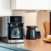 Nescafe coffee machine price comparison showing a modern drip coffee maker and a kettle on kitchen counter