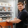 Technician performing step-by-step vending machine maintenance for offices on a snack vending machine