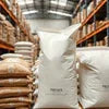 Premium coffee machine in Noida warehouse with large sacks of coffee beans stacked on pallets