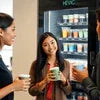 People enjoying coffee using coffee machine rental Noida in an office break room