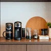 Office coffee machine Noida featuring sleek black model with cups and accessories on wooden countertop