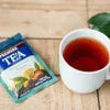Amazon Plus Tea Premix 1 kg Supplier pack with brewed tea cup on wooden surface