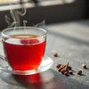 Amazon Plus tea premix 1kg served hot in a clear glass cup with spices on the side