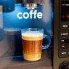 Premium office coffee blend Noida served in clear glass mug from coffee vending machine