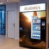 Atlantis coffee vending machine with illuminated sign and stocked beverage display in office lobby