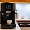 Black coffee machine brewing a cup on kitchen counter showing coffee machine price in Gurugram