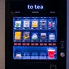 Automatic tea and coffee vending machine with multiple drink options displayed on screen