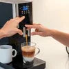 Touchless coffee machines in Gurugram dispensing coffee into a glass cup with hands nearby