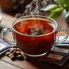 Clear cup of steaming tea premix served with chocolate pieces and coffee beans for cafe vending