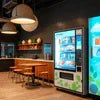 Atlantis 2 Lane machine vending drinks in modern office lounge with wooden tables and pendant lights