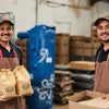 Two workers packing brown coffee premix bags in a warehouse for coffee premix supplier Mizoram vending and office use