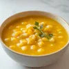 Bowl of bright yellow Instant Sweet Corn Soup Premix garnished with herbs for office or vending use