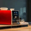 Red and black ATLANTIS COFFEE MACHINE model for office use on wooden countertop with two cups