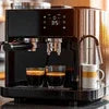 Atlantis Neo Coffee Machine Tripura black model for office use with two espresso cups and milk frother