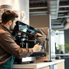 Barista using a black commercial coffee machine for Coffee Machine Installation in Gurgaon in a modern cafe