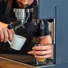 Barista using black espresso coffee machine for office serving from coffee machine supplier Delhi