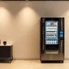 Black Veeco Vendo 680 coffee vending machine in office setting with illuminated interior display