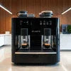Atlantis coffee machine Delhi black dual cup office vending model with wood panel background