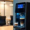Black touchless coffee machine Delhi with digital display making layered latte in office setting