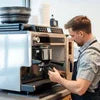Barista using black commercial coffee machine for office use with commercial coffee machine service Noida