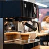 Black DeLonghi office coffee machine brewing espresso with two cups for office coffee machine rental Noida