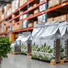 Amazon Plus tea premix distributor Delhi packaging showing silver bags with green leaf design in warehouse setting