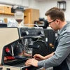 Technician repairing a black espresso coffee machine for office use with laptop, coffee machine repair Noida