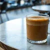 Amazon Plus coffee premix Gorakhpur glass cup with creamy coffee on a cafe table for office or vending use