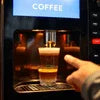 Close-up of a black coffee vending machine Noida installation preparing a cup of coffee in an office setting