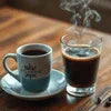 Atlantis coffee premix Bhavnagar steaming cup and glass of black coffee on wooden table