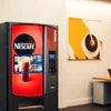 Red and black Nescafe Machine Ghaziabad vending coffee machine in office setting with painting on wall