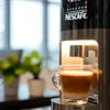 Nescafe Machine Faridabad black model brewing coffee in office setting with glass cup