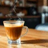 Glass cup of coffee premix on wooden table in a cozy cafe setting for Coffee Premix in Noida