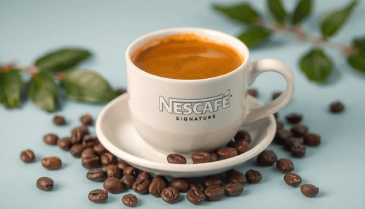 A cup of Nescafe signature coffee with coffee beans