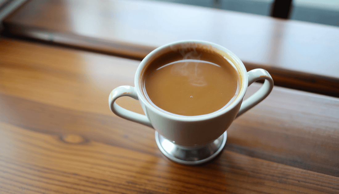 A steaming cup of Thai coffee on a wooden table