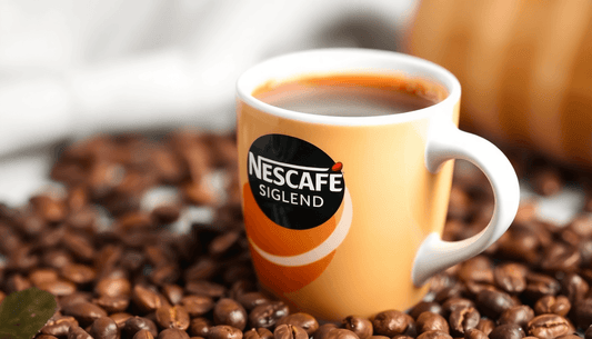 A cup of Nescafe Signature Blend coffee with coffee beans