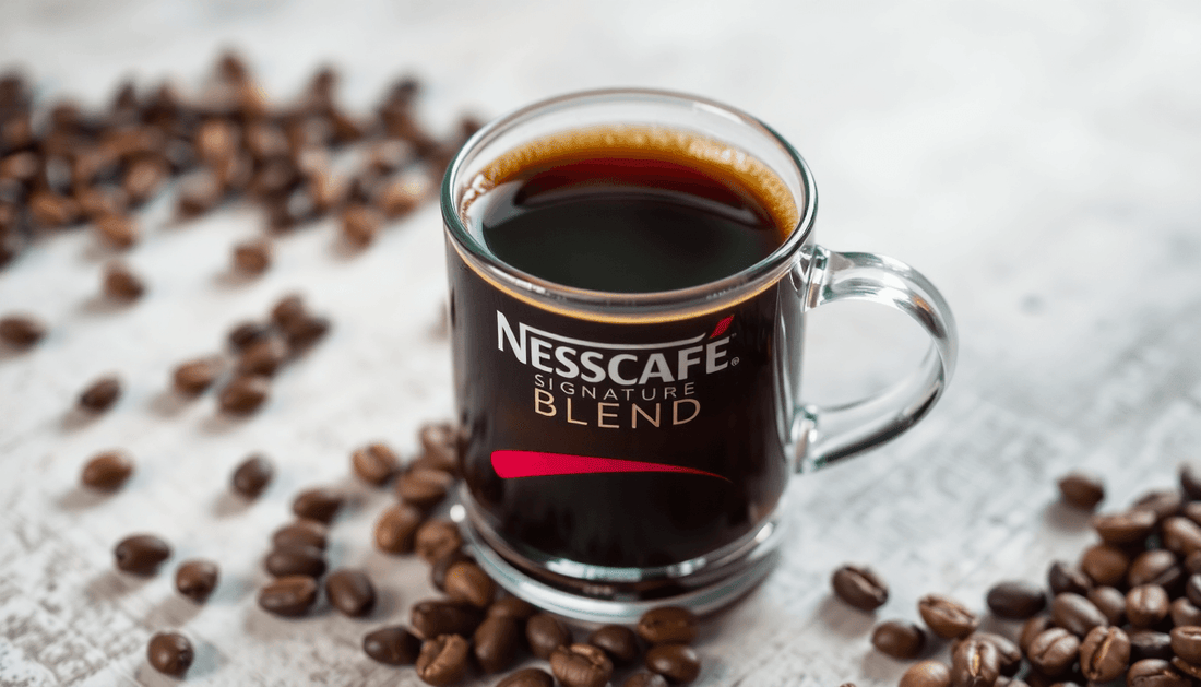 A cup of Nescafe Signature Blend coffee with coffee beans