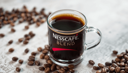 A cup of Nescafe Signature Blend coffee with coffee beans