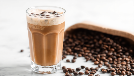 A cold frappé coffee in a clear glass with coffee beans