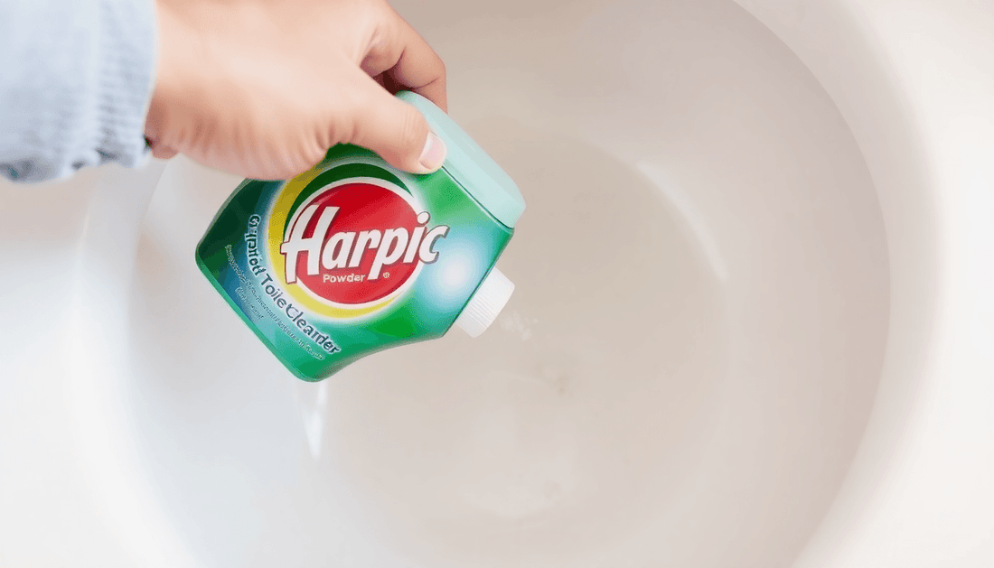 A hand pouring Harpic toilet cleaner powder into toilet bowl