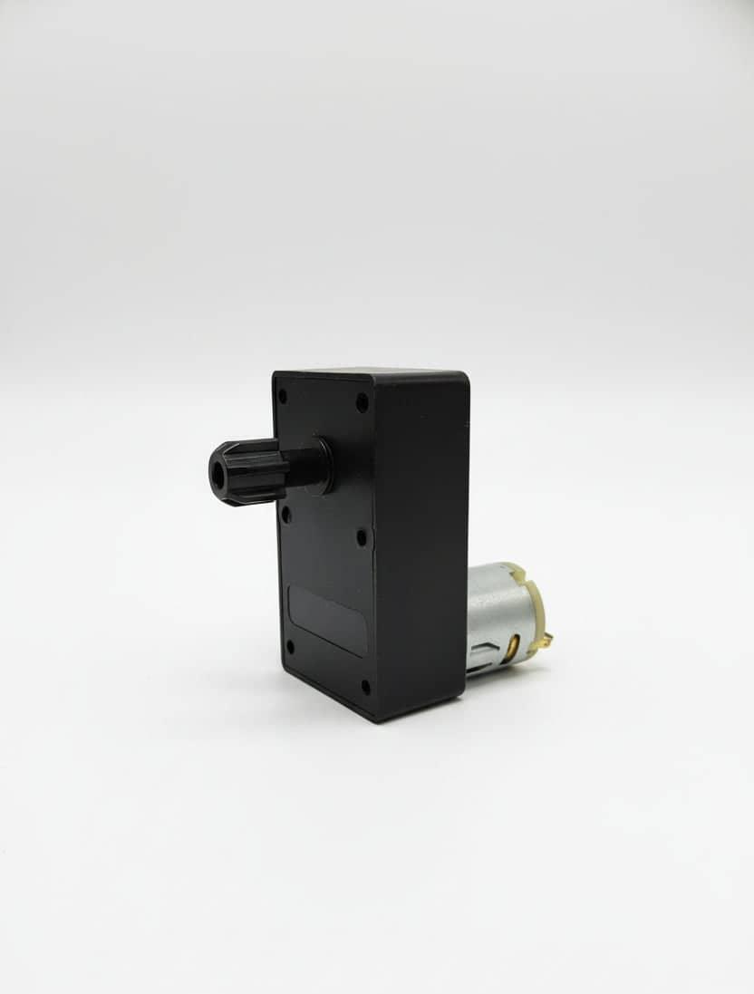 Black mechanical component part with a cylindrical motor attached on a white background Amazon tea premix Noida