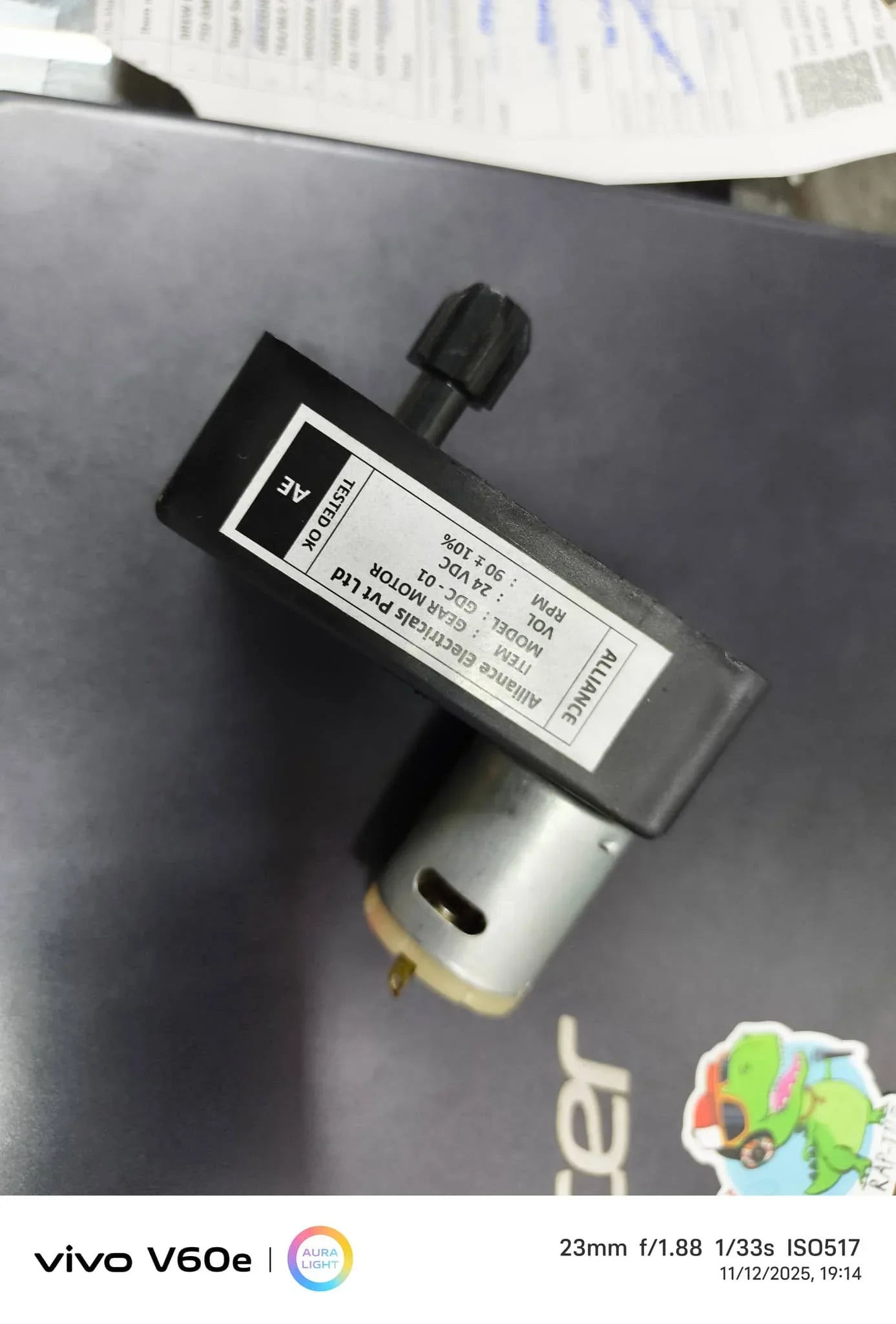 Close-up of a small electric water pump on a black surface with Amazon tea premix Noida label visible