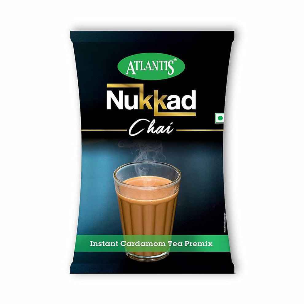 Atlantis Nukkad cardamom tea premix packet with steaming cup of chai on black background